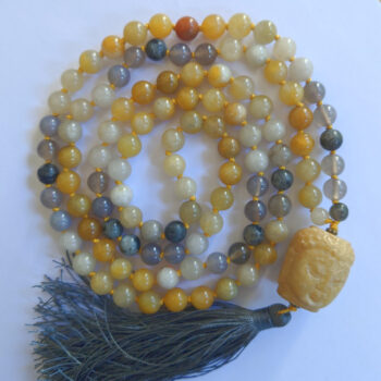 Kollased ja hallid ümmargused kristalli pärlitest vaimne kaelakee ehk Mala palvehelmed. Kollane Buddha pea. Hall siiditutt. Heledal taustal