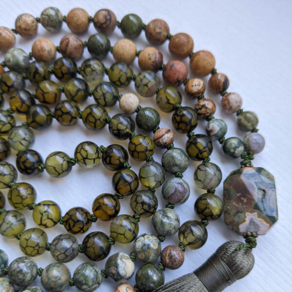 Rohelised ja pruunid kristallid pärlid. Roheline Rüoliit kristall Guru ehk õpetaja kivi. 108 pärliga spirituaalne Mala palvehelmed kaelakee. Samblaroheline tutt. Heledal taustal