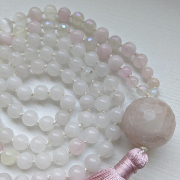 roosad ja valged ümmargused kristallid pärlid. Kvartsi süda Guru ehk õpetaja kivi. 108 pärliga spirituaalne kaelakee ehk Mala palvehelmed. Roosa tutt. Heledal taustal