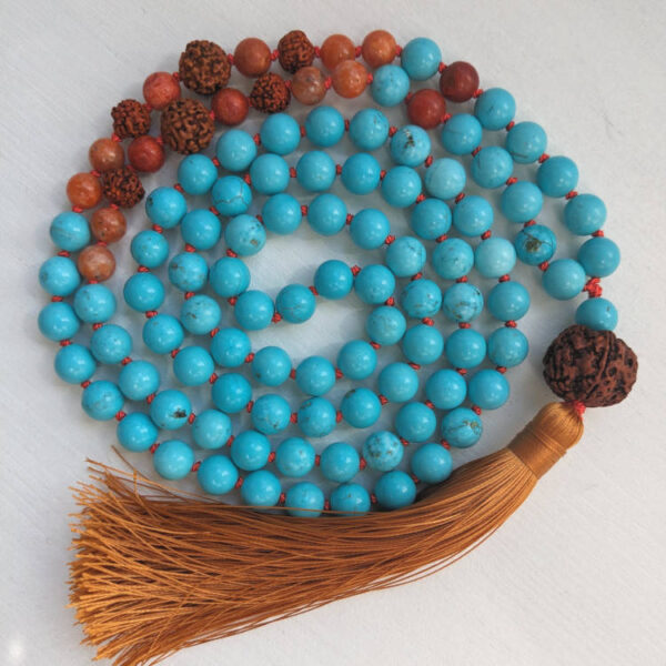 Sinised ja oranzid ümmargused kristallid pärlid. Pruun Rudraksha seeme Guru ehk õpetaja kivi. 108 pärliga spirituaalne Mala palvehelmed kaelakee. Oranz tutt. Heledal taustal