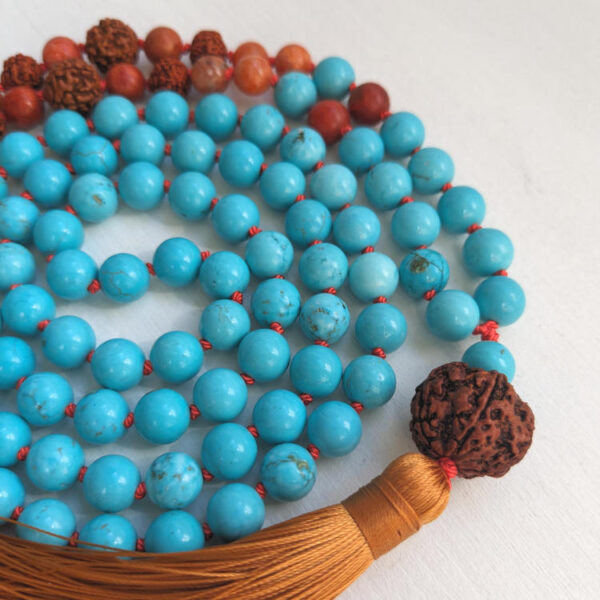 Sinised ja oranzid ümmargused kristallid pärlid. Pruun Rudraksha seeme Guru ehk õpetaja kivi. 108 pärliga spirituaalne Mala palvehelmed kaelakee. Oranz tutt. Heledal taustal