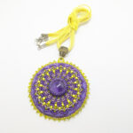 Lillade helmestega tikitud Mandala kaelakee. Keskel on AMETÜST kristallist südamik. Mandala on loodud helmestikandina. Kollane pael. heledal taustal.