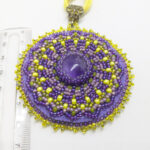 Lillade helmestega tikitud Mandala kaelakee. Keskel on AMETÜST kristallist südamik. Mandala on loodud helmestikandina. Kollane pael. heledal taustal.
